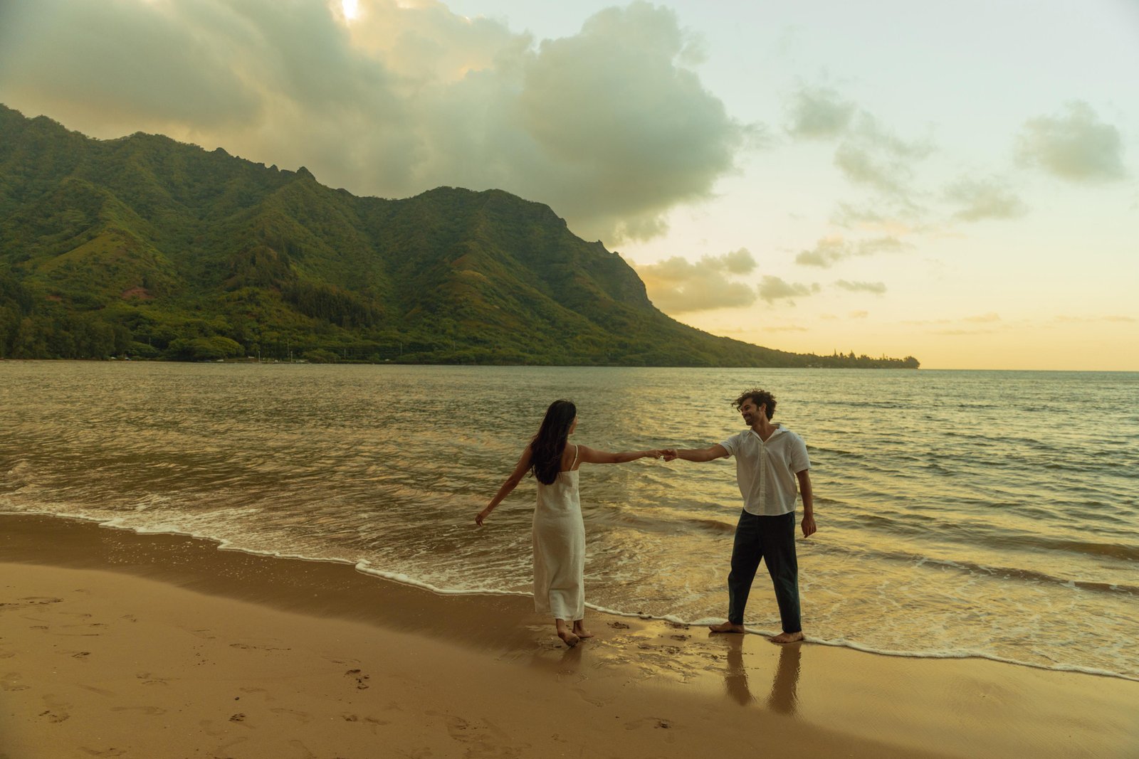 Couple holding hands on a beach at sunset